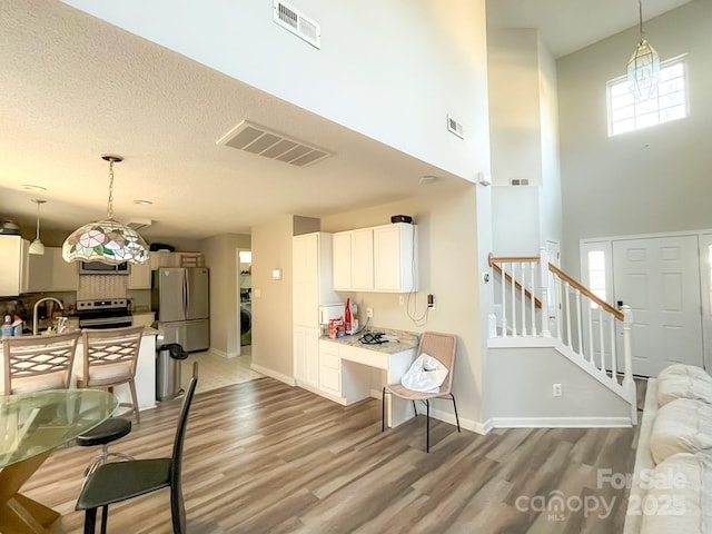 kitchen featuring appliances with stainless steel finishes, sink, pendant lighting, and light wood-type flooring