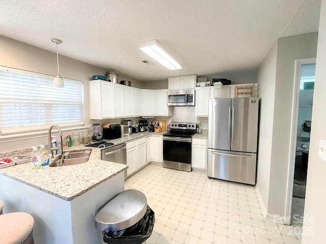 kitchen with a kitchen bar, sink, white cabinetry, decorative light fixtures, and appliances with stainless steel finishes