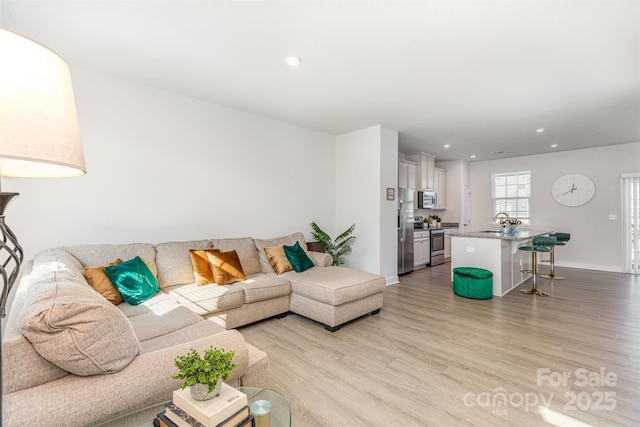 living area with baseboards, light wood-style flooring, and recessed lighting