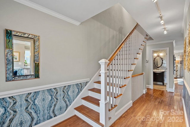 stairs featuring hardwood / wood-style flooring, track lighting, and ornamental molding