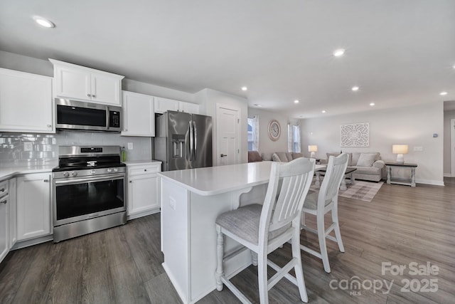 kitchen featuring appliances with stainless steel finishes, a center island, white cabinets, and backsplash