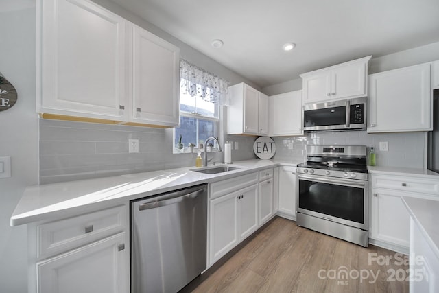 kitchen featuring white cabinetry, sink, light hardwood / wood-style flooring, and stainless steel appliances