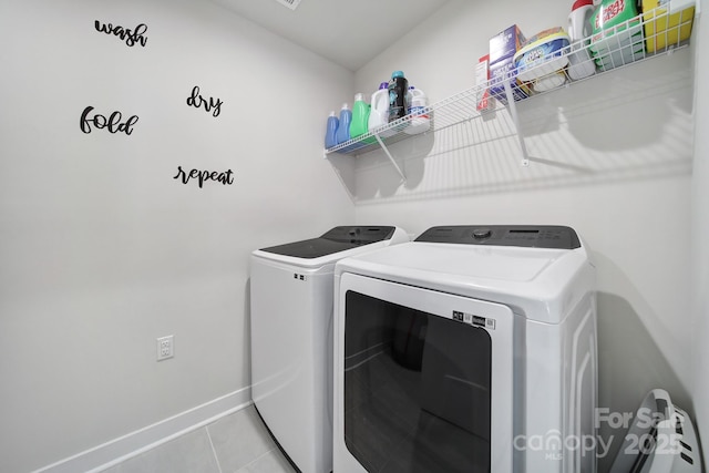 clothes washing area featuring light tile patterned flooring and separate washer and dryer