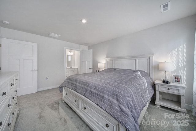 bedroom with ensuite bathroom and light carpet