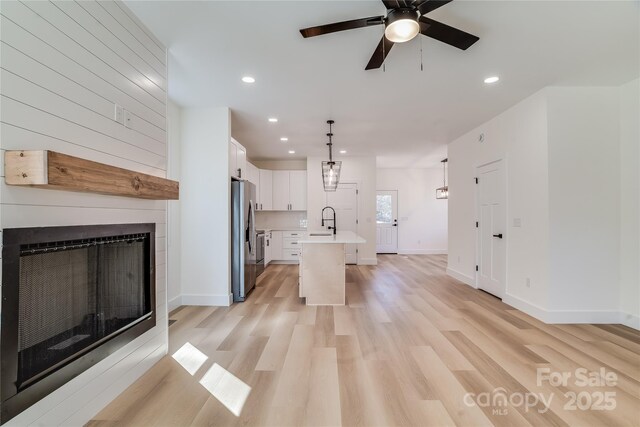 kitchen featuring a large fireplace, a sink, light wood-style floors, light countertops, and freestanding refrigerator