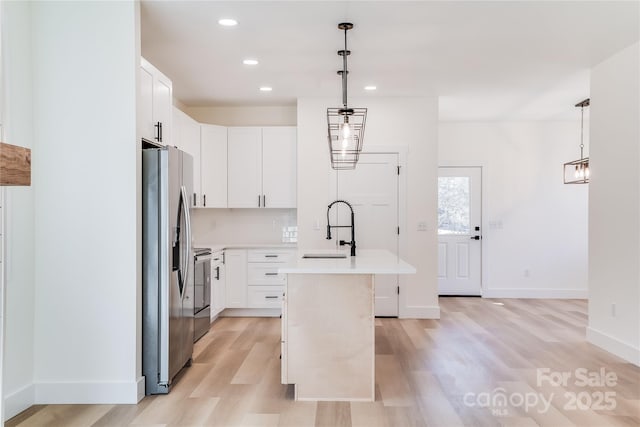 kitchen featuring a center island with sink, stainless steel fridge with ice dispenser, light wood-style flooring, light countertops, and a sink