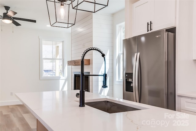 kitchen featuring light stone counters, white cabinets, and stainless steel fridge