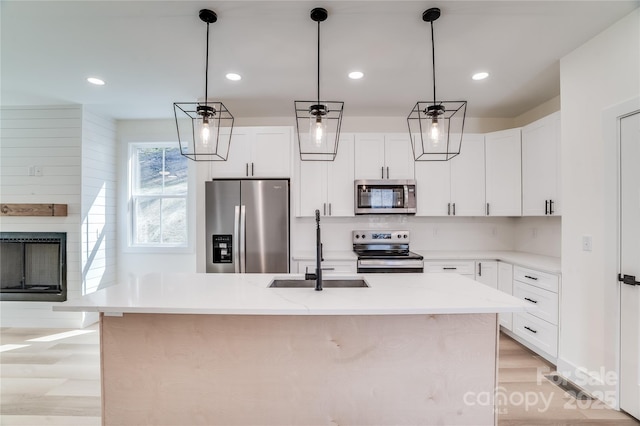 kitchen featuring a fireplace, pendant lighting, stainless steel appliances, and a sink