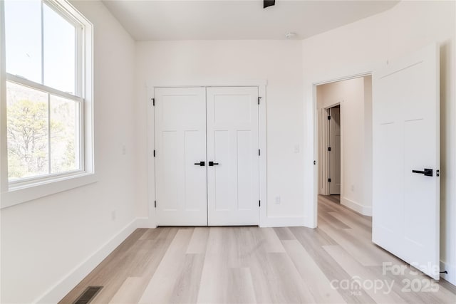 unfurnished bedroom with light wood finished floors, baseboards, and visible vents