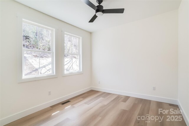 empty room with baseboards, visible vents, ceiling fan, and light wood finished floors