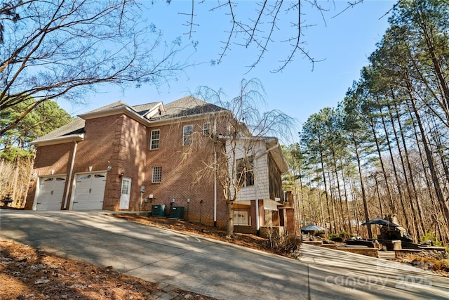 view of side of home with a garage and central AC unit