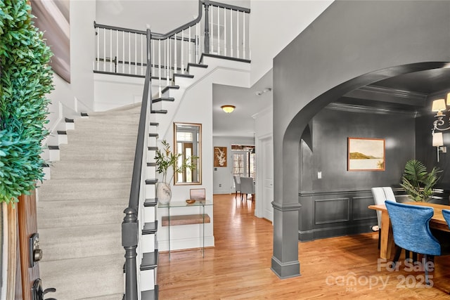 foyer entrance featuring crown molding, hardwood / wood-style flooring, and a towering ceiling