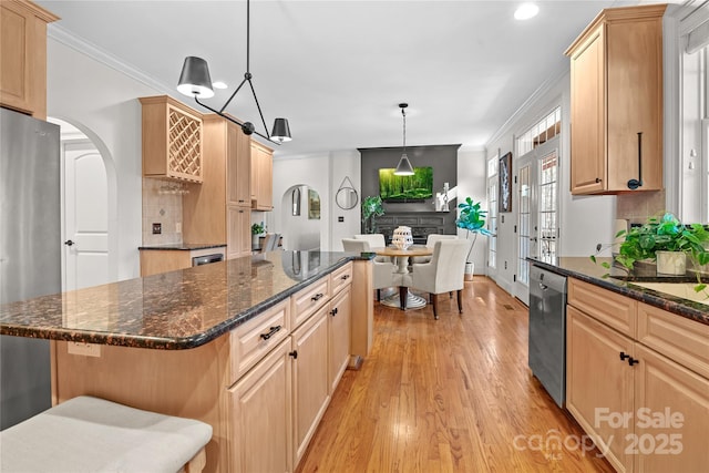 kitchen featuring light brown cabinetry, crown molding, a kitchen island, pendant lighting, and stainless steel appliances