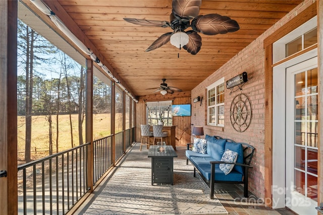 sunroom / solarium with lofted ceiling, wooden ceiling, and ceiling fan