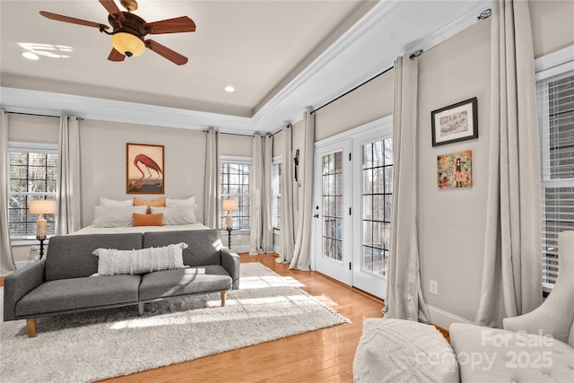 bedroom featuring crown molding, ceiling fan, access to exterior, a raised ceiling, and light wood-type flooring