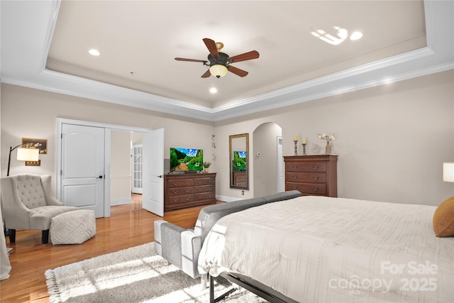 bedroom featuring ornamental molding, light hardwood / wood-style floors, and a raised ceiling