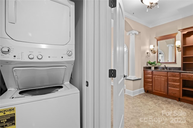 clothes washing area with sink, crown molding, light tile patterned floors, decorative columns, and stacked washer / dryer