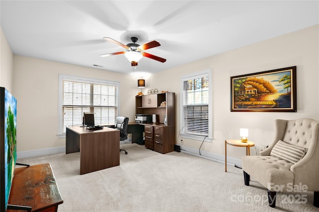 home office with a healthy amount of sunlight, light carpet, and ceiling fan