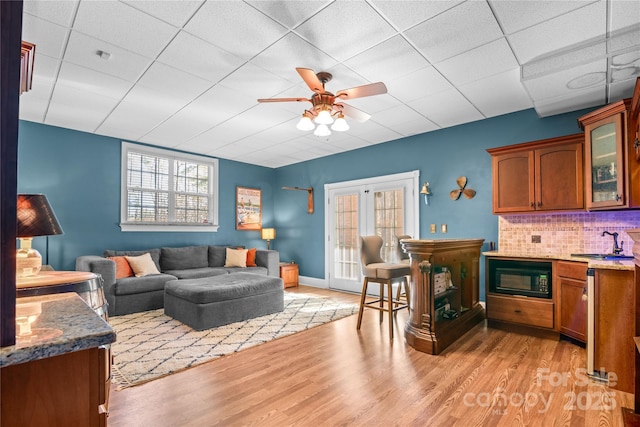 living room with plenty of natural light, sink, and light hardwood / wood-style flooring