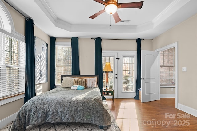 bedroom featuring a tray ceiling, access to outside, ornamental molding, and light hardwood / wood-style floors