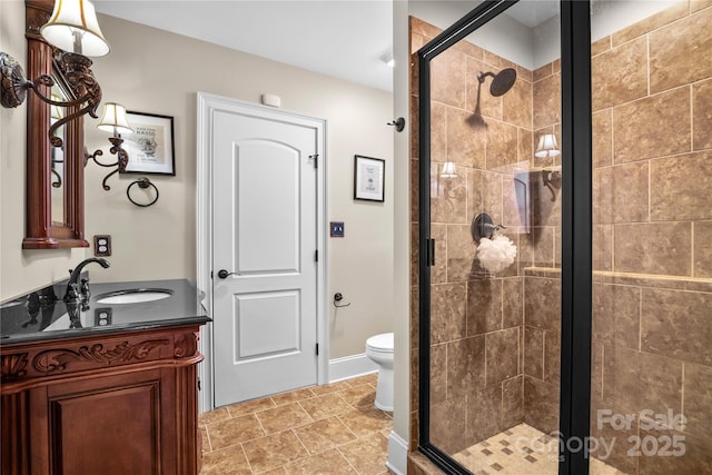 bathroom featuring a shower with door, vanity, and toilet