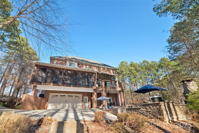 view of front facade featuring a balcony, a garage, and a sunroom