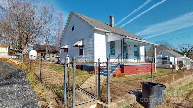 view of home's exterior featuring a fenced front yard, covered porch, a chimney, a gate, and a shingled roof