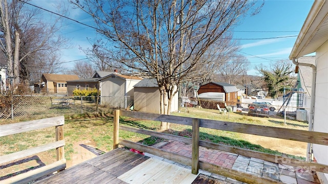 wooden terrace featuring an outdoor structure, a lawn, and fence