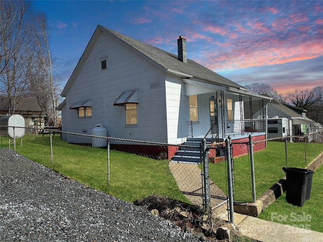 view of home's exterior featuring a chimney, a yard, a gate, a fenced front yard, and covered porch