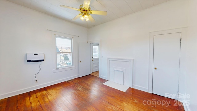 interior space with baseboards, visible vents, a ceiling fan, and wood finished floors