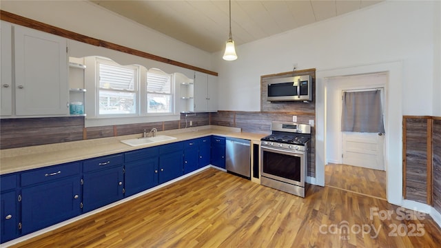 kitchen with hanging light fixtures, white cabinetry, stainless steel appliances, a sink, and light countertops