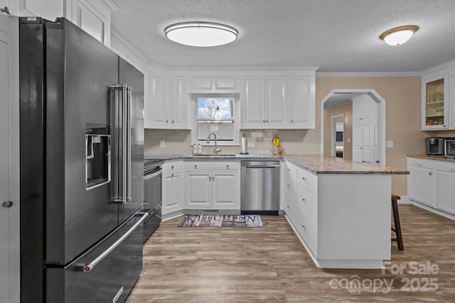 kitchen with a kitchen bar, kitchen peninsula, white cabinets, and appliances with stainless steel finishes