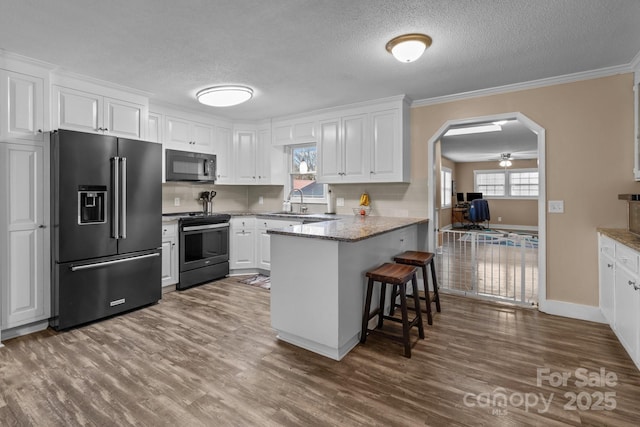 kitchen with a breakfast bar area, black appliances, kitchen peninsula, and white cabinets