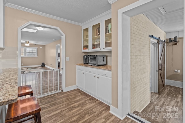 kitchen featuring hardwood / wood-style flooring, a barn door, a textured ceiling, and white cabinets