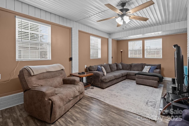 living room with dark hardwood / wood-style flooring, ceiling fan, and a wood stove