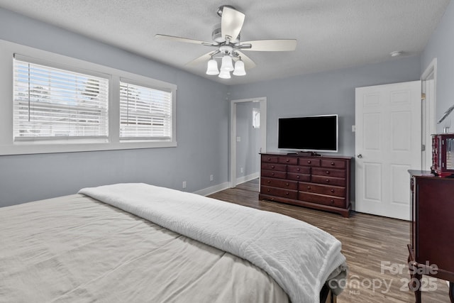 bedroom with ceiling fan, dark wood-type flooring, and a textured ceiling