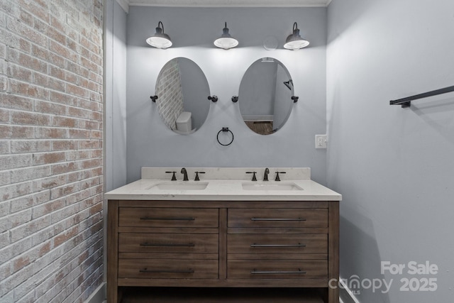 bathroom with vanity and brick wall