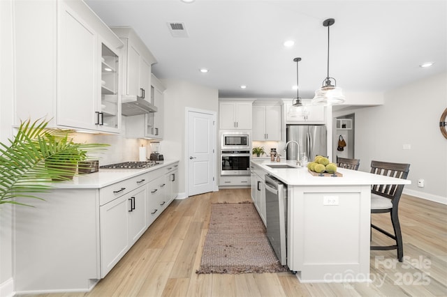 kitchen with pendant lighting, sink, a breakfast bar, a kitchen island with sink, and stainless steel appliances