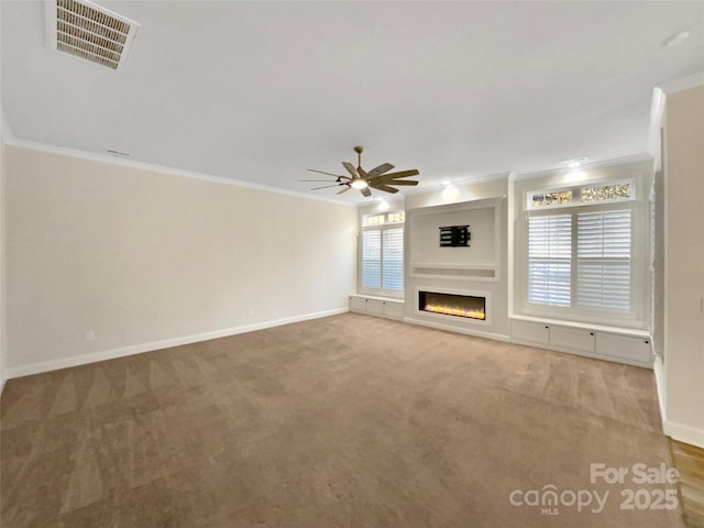 unfurnished living room featuring carpet, ceiling fan, crown molding, and a wealth of natural light