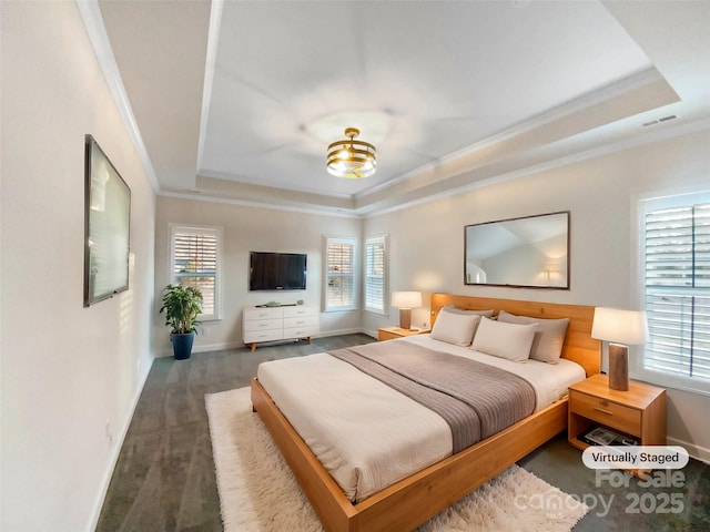 bedroom with a tray ceiling, multiple windows, and crown molding