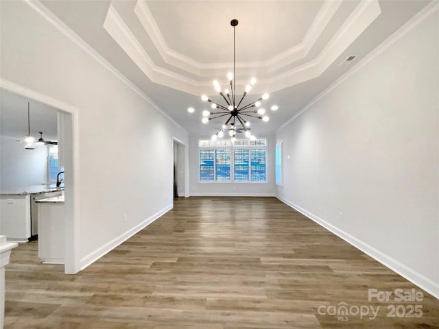 unfurnished dining area featuring a chandelier, crown molding, a raised ceiling, and hardwood / wood-style floors