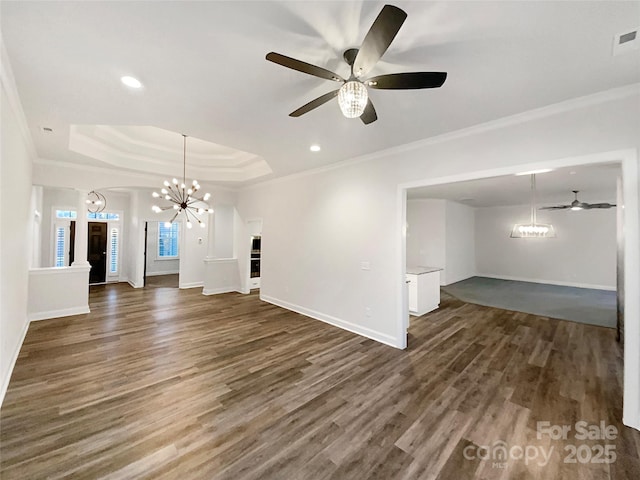 unfurnished living room with ceiling fan with notable chandelier, crown molding, a tray ceiling, and dark hardwood / wood-style flooring