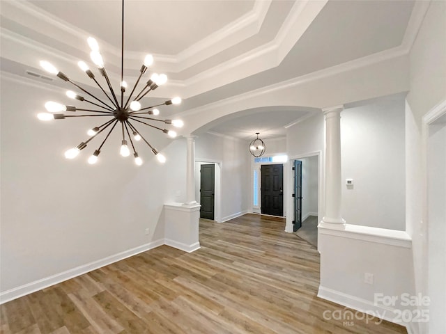 spare room featuring a chandelier, hardwood / wood-style floors, a tray ceiling, ornamental molding, and ornate columns