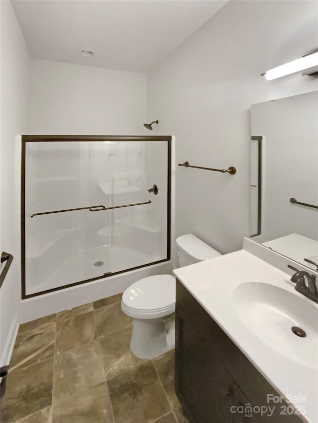 bathroom with vanity, a shower with door, and toilet