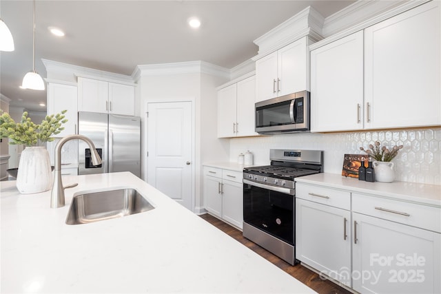 kitchen featuring appliances with stainless steel finishes, decorative light fixtures, white cabinetry, sink, and crown molding