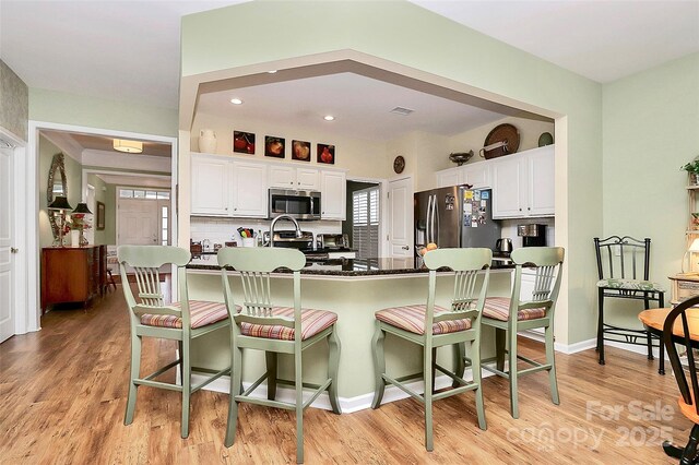9119 Gander Dr, Charlotte, NC 28277 - kitchen with decorative backsplash, light hardwood / wood-style flooring, white cabinets, and appliances with stainless steel finishes