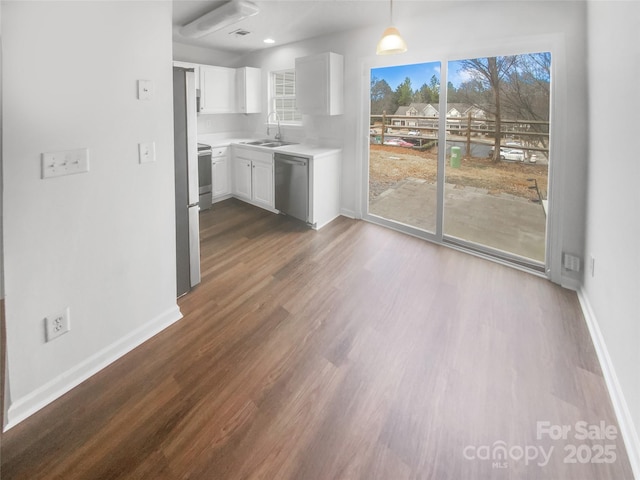 kitchen featuring white cabinetry, sink, hanging light fixtures, hardwood / wood-style flooring, and stainless steel dishwasher