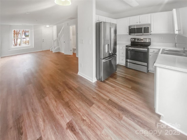 kitchen featuring white cabinetry, stainless steel appliances, sink, and light wood-type flooring