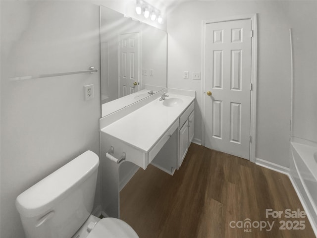 bathroom featuring vanity, hardwood / wood-style flooring, a bathing tub, and toilet