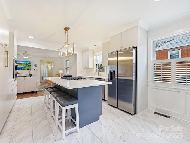 kitchen featuring pendant lighting, a breakfast bar, backsplash, stainless steel appliances, and a center island